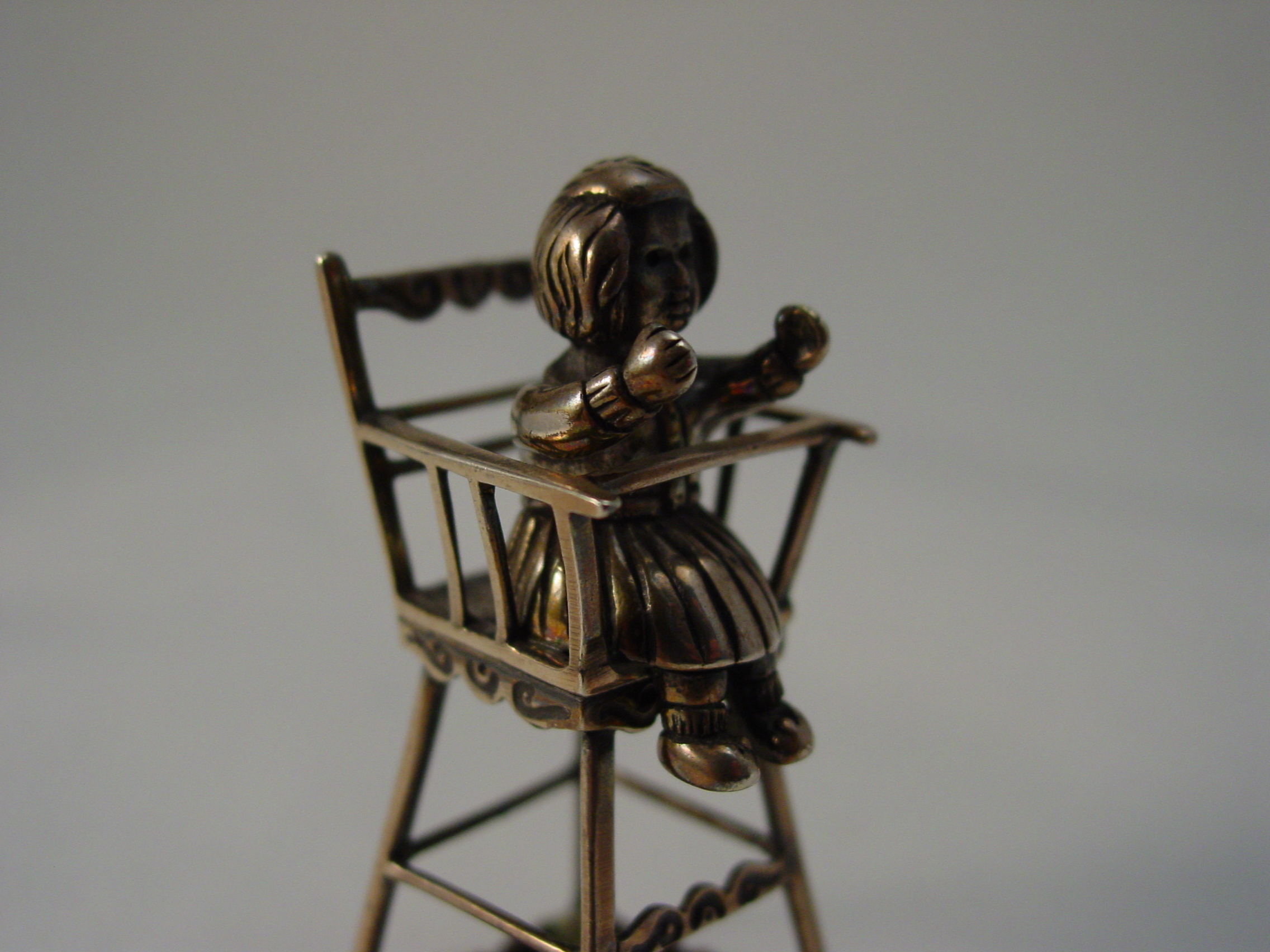 Zilveren miniatuur, meisje in kinderstoel