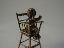 Zilveren miniatuur, meisje in kinderstoel