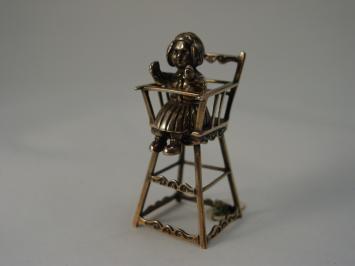Zilveren miniatuur, meisje in kinderstoel